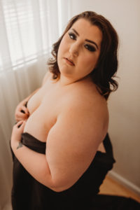 Sacramento boudoir photography with plus size woman in black satin sheet for implied nude art