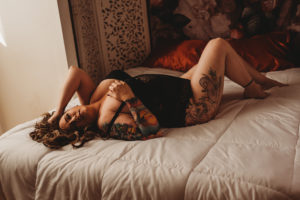 Folsom boudoir photography tattooed woman on bed in black lace