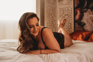 Folsom boudoir photography tattooed woman on bed in black lace