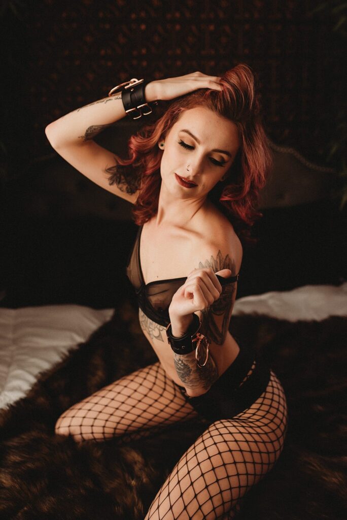 In this alluring and daring boudoir photograph captured by Limitless Boudoir in Sacramento CA, a thin woman is featured wearing black fishnet stockings, black stilettos, and black cuffs surrounding her wrists. This photoshoot is tailored to those searching for a boudoir photography experience that incorporates bondage, fetish, and BDSM elements. The woman's captivating expression, commanding presence, and erotic attire are perfect for women in the Sacramento area who crave a daring and thrilling boudoir experience. The high-quality photography highlights the beauty of the woman's curves, while the black cuffs demonstrate an edgy and daring touch. This photoshoot embodies a setting that encourages creative expression and self-love, allowing women to explore and connect with their sensual sides in a safe and empowering environment.