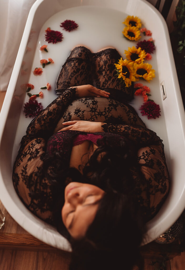 Radiant mother-to-be cradling baby bump amidst floral petals, captured in heartfelt maternity photoshoot in Sacramento california.